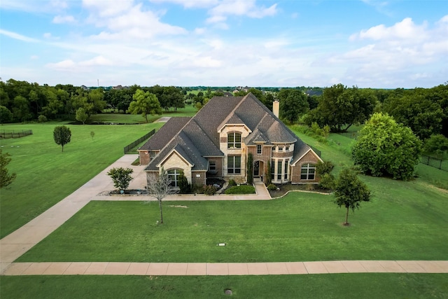 french provincial home featuring a front yard, stone siding, and a chimney