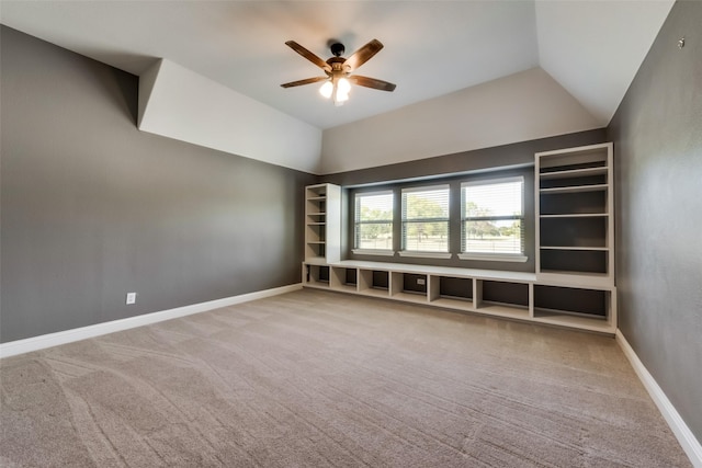 carpeted empty room with lofted ceiling, ceiling fan, and baseboards