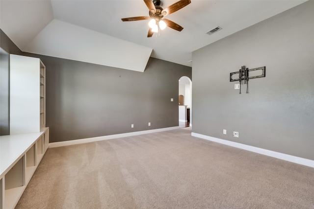 interior space featuring arched walkways, light carpet, visible vents, baseboards, and a ceiling fan