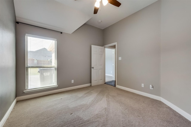 unfurnished room with light carpet, vaulted ceiling, and baseboards