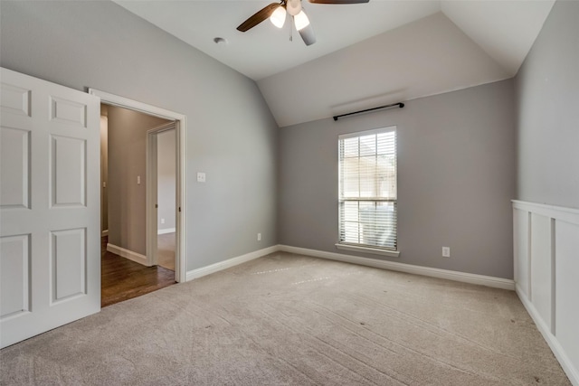 spare room with a ceiling fan, lofted ceiling, light colored carpet, and baseboards