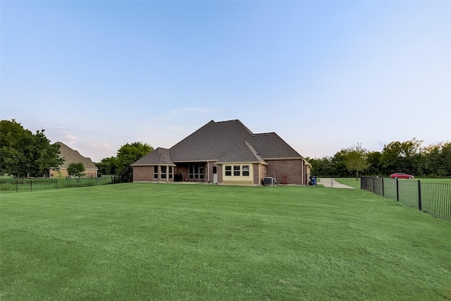 rear view of property featuring brick siding, a lawn, and a fenced backyard