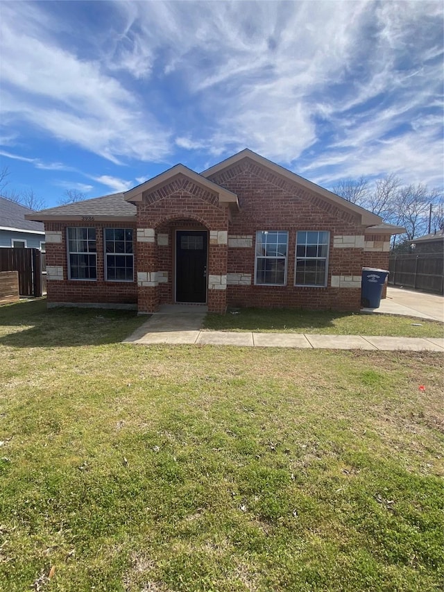 ranch-style home featuring fence, a front lawn, and brick siding