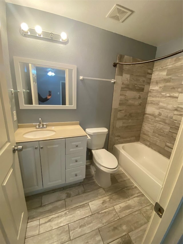 bathroom featuring shower / bathtub combination, visible vents, toilet, wood tiled floor, and vanity