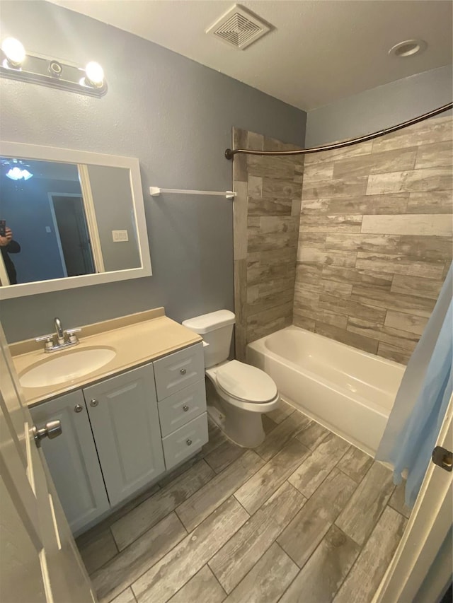 bathroom featuring toilet, wood finish floors, shower / bath combination, vanity, and visible vents