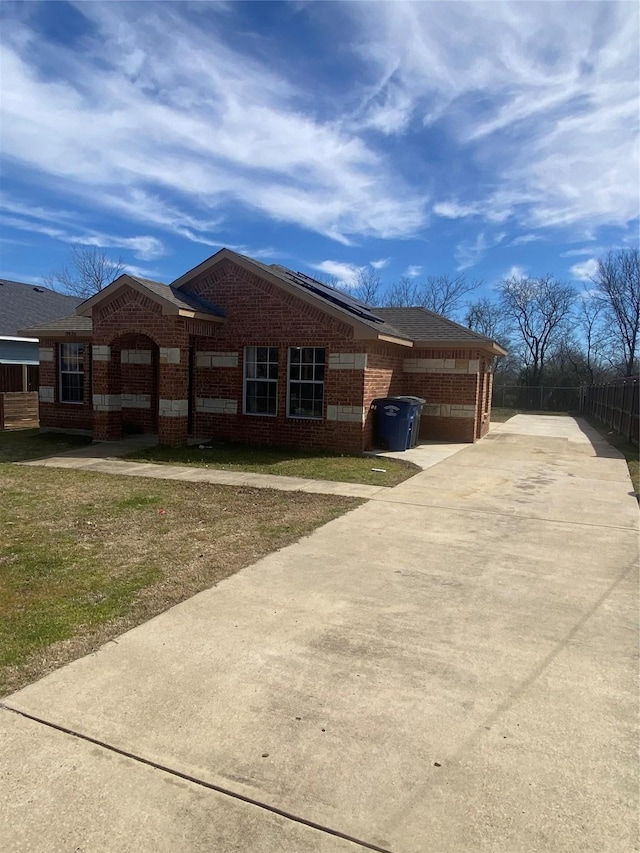 view of property exterior with driveway, a yard, fence, and brick siding