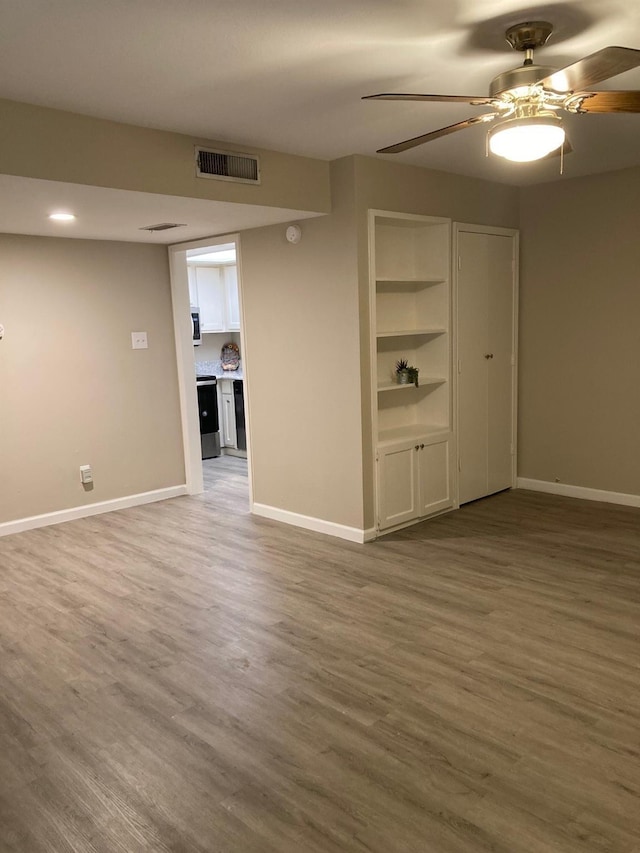 unfurnished room with a ceiling fan, baseboards, visible vents, and wood finished floors