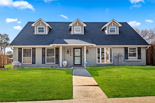 view of front of property with brick siding, a shingled roof, and a front yard