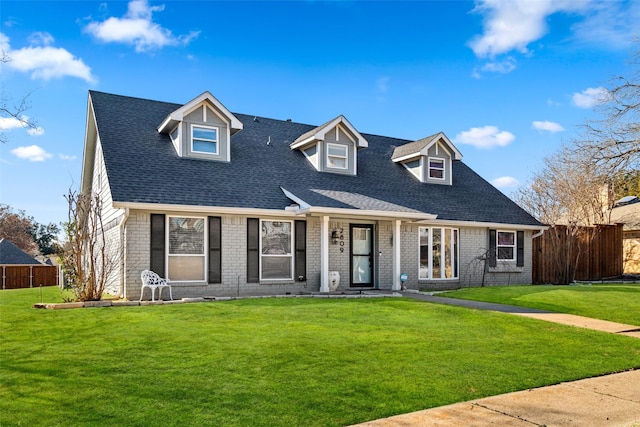 cape cod-style house with brick siding, a front yard, and fence