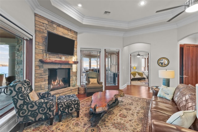 living area featuring arched walkways, ceiling fan, a fireplace, wood finished floors, and visible vents