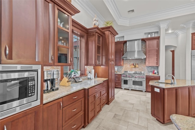 kitchen with visible vents, wall chimney exhaust hood, glass insert cabinets, stainless steel appliances, and a sink