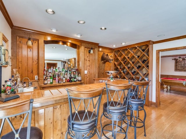 bar featuring ornamental molding, indoor wet bar, light wood-style flooring, recessed lighting, and a sink