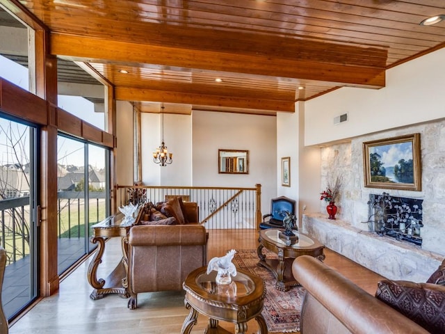 living area with visible vents, beamed ceiling, wooden ceiling, an inviting chandelier, and wood finished floors