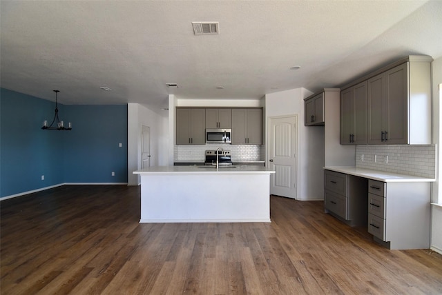 kitchen with visible vents, stainless steel microwave, light countertops, and a sink