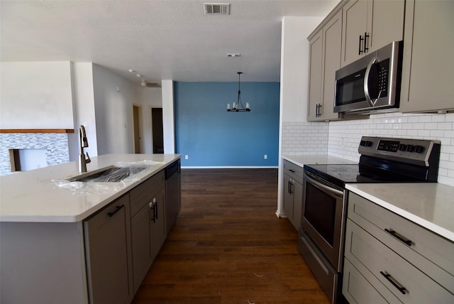 kitchen featuring pendant lighting, stainless steel appliances, gray cabinets, visible vents, and a sink