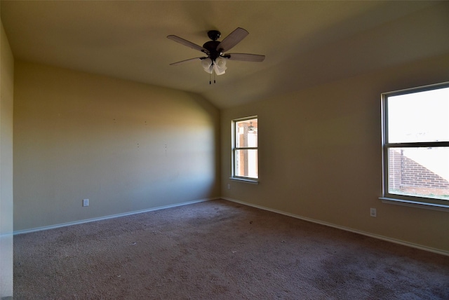 carpeted spare room featuring a ceiling fan, lofted ceiling, plenty of natural light, and baseboards