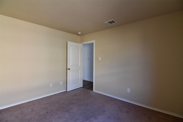 unfurnished room with carpet floors, visible vents, and baseboards