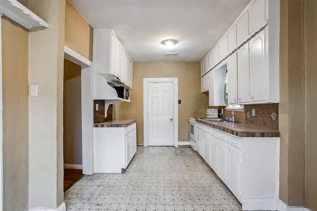 kitchen with dark countertops, electric stove, and white cabinets