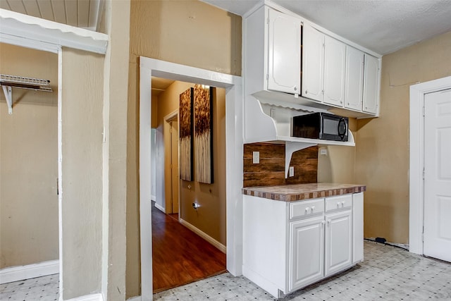 kitchen with black microwave, white cabinets, and light floors