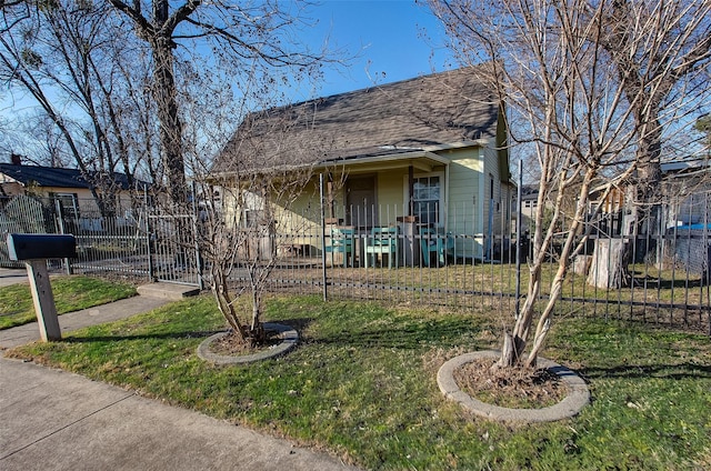 view of front facade with roof with shingles, a front lawn, and a fenced front yard