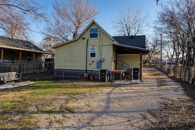 rear view of property featuring roof with shingles and fence