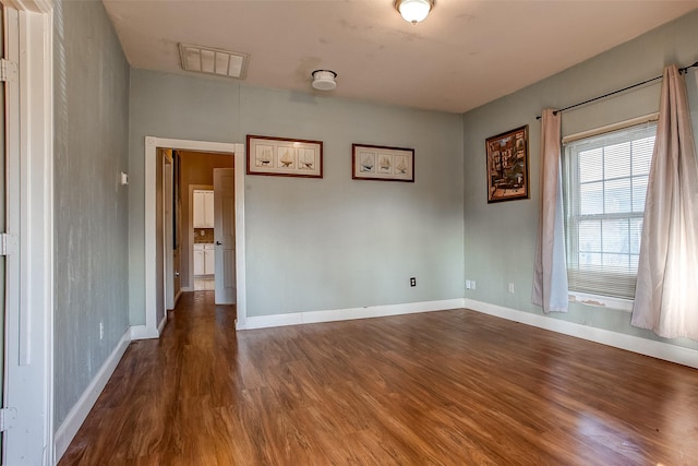 spare room featuring baseboards, visible vents, and dark wood-style flooring