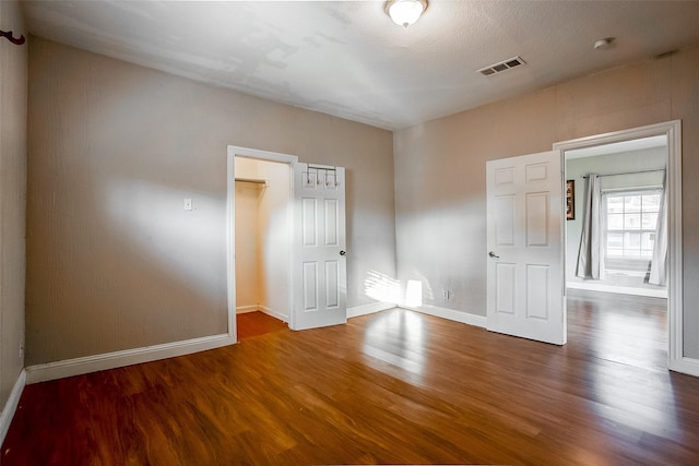 spare room featuring baseboards, visible vents, and wood finished floors