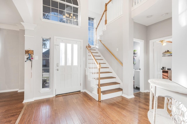 foyer entrance featuring stairs, hardwood / wood-style flooring, baseboards, and a towering ceiling