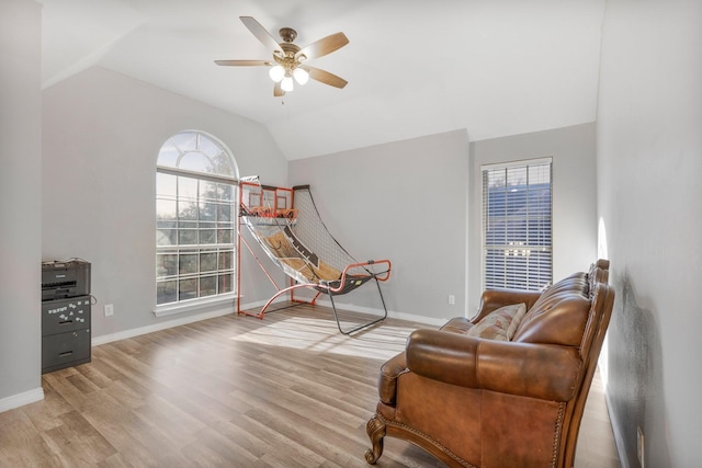 living area featuring ceiling fan, baseboards, wood finished floors, and vaulted ceiling