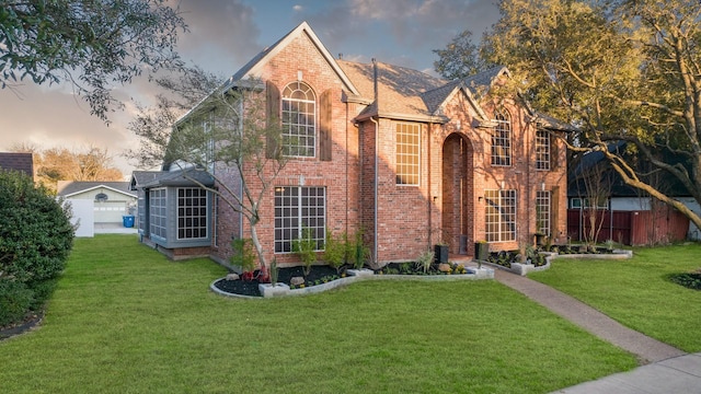 view of front of home with brick siding, a lawn, and fence