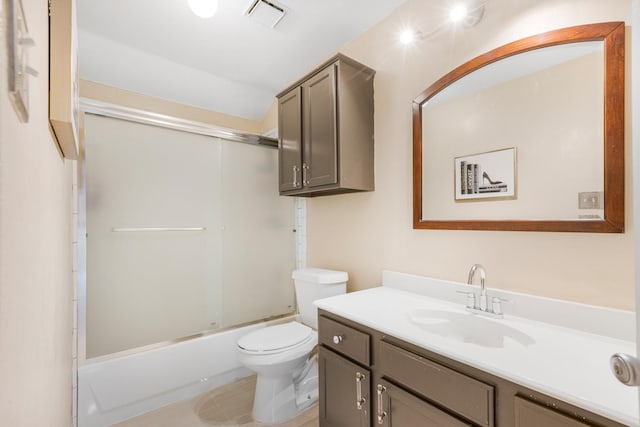 bathroom featuring visible vents, toilet, vanity, and bath / shower combo with glass door