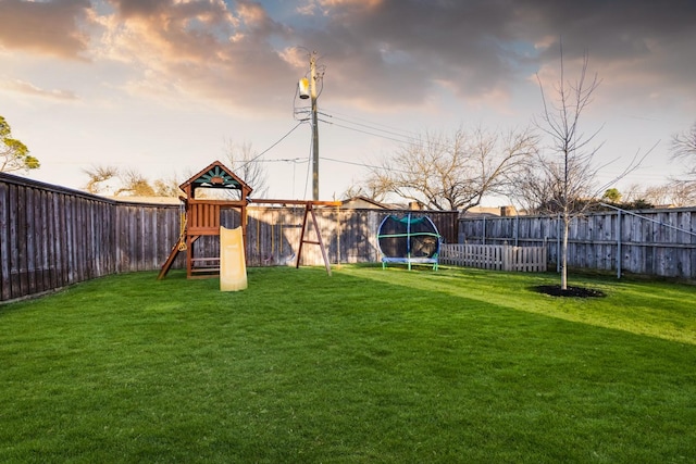 view of yard with a playground, a trampoline, and a fenced backyard