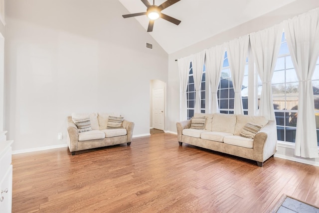 living area featuring visible vents, ceiling fan, baseboards, wood finished floors, and high vaulted ceiling