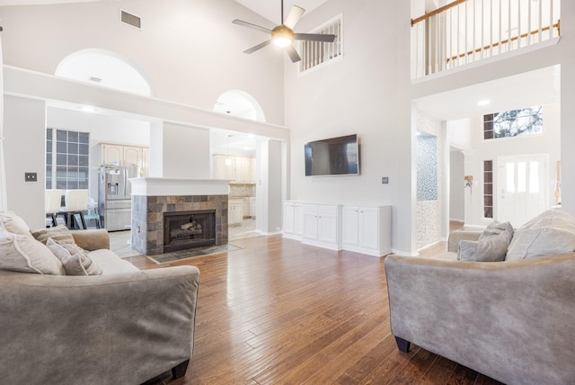 living area with visible vents, a ceiling fan, a fireplace, and hardwood / wood-style flooring