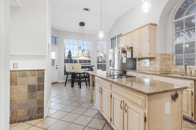 kitchen featuring visible vents, light brown cabinets, a sink, a kitchen island, and stainless steel fridge with ice dispenser