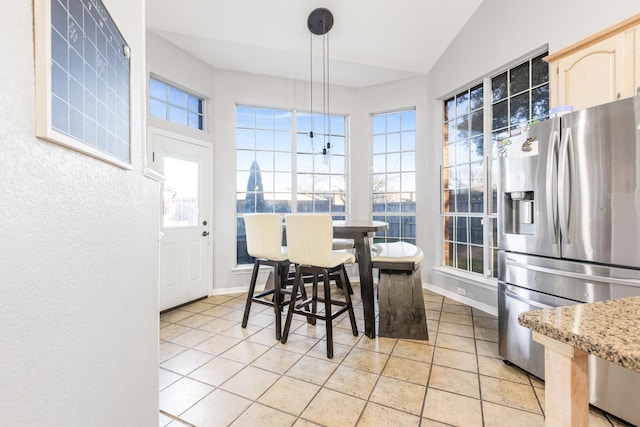 dining room with lofted ceiling, light tile patterned flooring, and baseboards