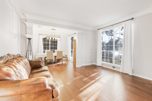 living area featuring crown molding, a notable chandelier, and wood finished floors