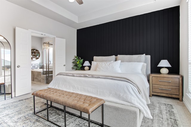 bedroom featuring light carpet, ceiling fan, a raised ceiling, and ensuite bathroom