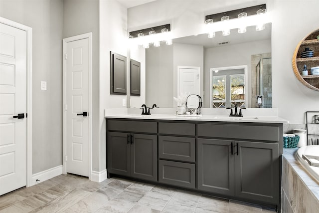 full bathroom featuring double vanity, a relaxing tiled tub, a sink, and visible vents