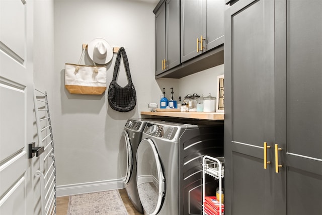 clothes washing area featuring cabinet space, baseboards, light wood-style floors, and washing machine and clothes dryer