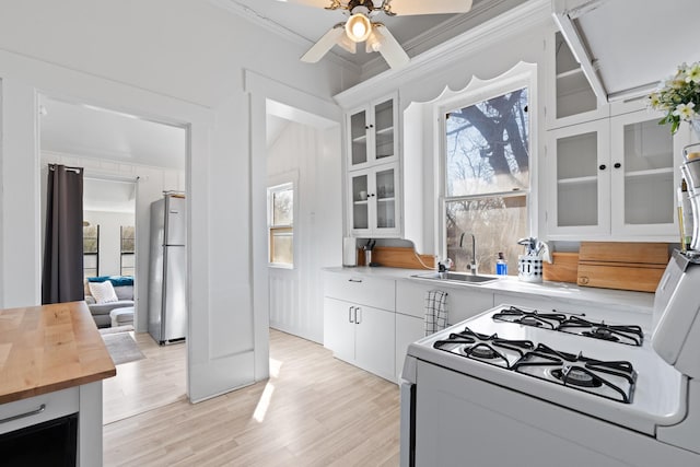 kitchen featuring a wealth of natural light, freestanding refrigerator, butcher block counters, and a sink