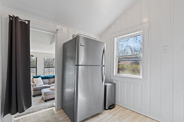 kitchen with lofted ceiling, light wood finished floors, plenty of natural light, and freestanding refrigerator