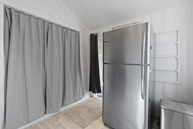 kitchen featuring lofted ceiling, light wood-style flooring, freestanding refrigerator, and white cabinetry