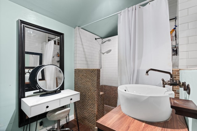 bathroom featuring a tile shower and a sink