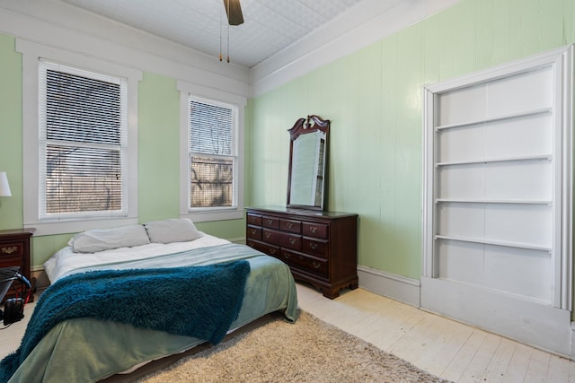 bedroom with multiple windows, a ceiling fan, and wood finished floors