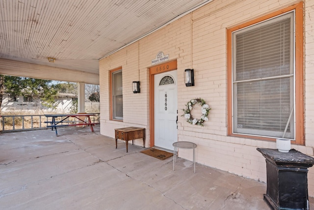 property entrance featuring a porch and brick siding