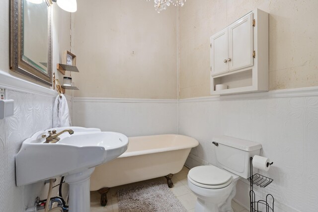 bathroom featuring a wainscoted wall, tile patterned flooring, a freestanding tub, and toilet