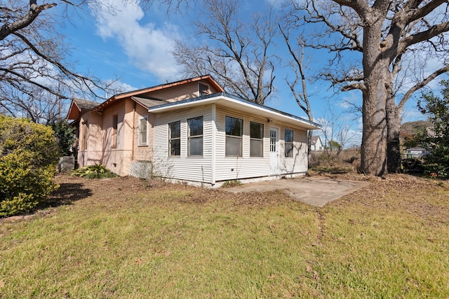 view of side of property featuring a yard and a patio