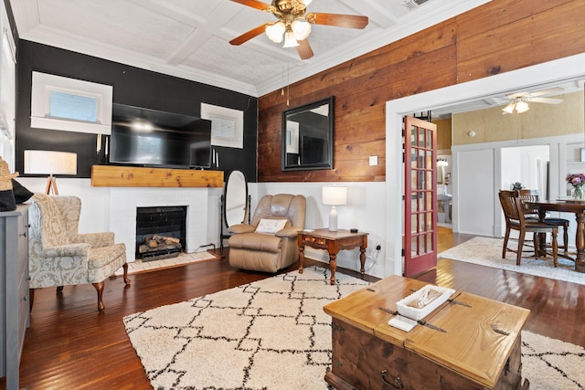 living area with wood-type flooring, a ceiling fan, a brick fireplace, wood walls, and coffered ceiling