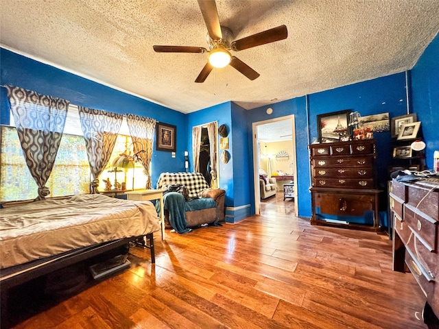 bedroom featuring a textured ceiling, wood finished floors, and a ceiling fan